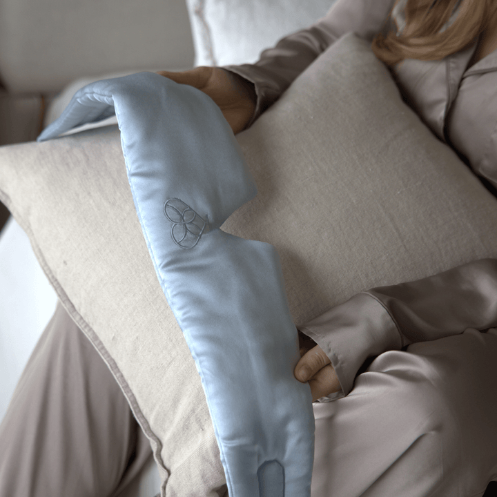 Masque de sommeil en soie bleu ciel tenu en main