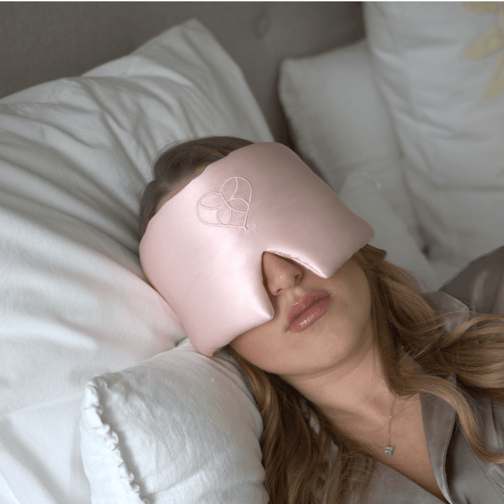 Femme dormant avec un masque de sommeil en soie rose clair